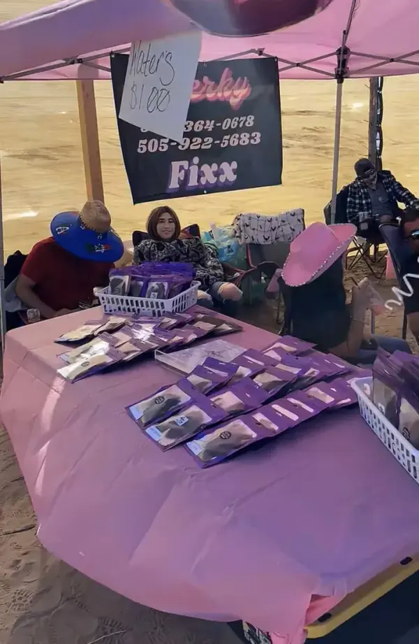 The Jerky Fixx booth with its sign and purple jerky bags