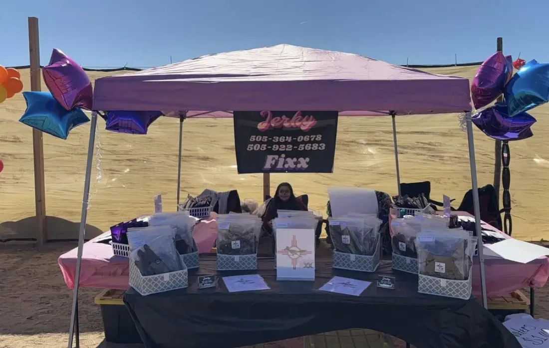 Jerky Fixx booth table set up under a pink canopy